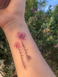 a woman's wrist with flowers on it and the word love written in cursive writing