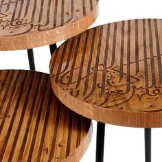 three round wooden tables with metal legs and arabic writing on the top, set against a white background