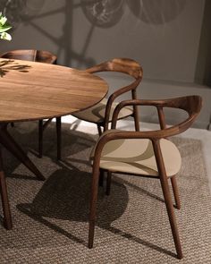 a wooden table with two chairs next to it and a flower vase on the table