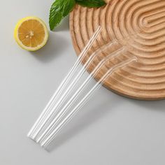 four straws and two lemon slices on a plate with mint leaves next to them