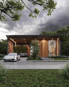 two cars are parked in front of a modern house with wood siding and glass windows