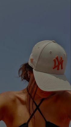 a woman wearing a new york yankees hat and black tank top with her hair blowing in the wind