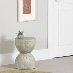 a small potted plant sitting on top of a cement table next to a door