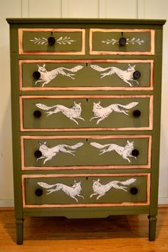 a green dresser with white dogs painted on it