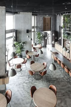 an empty restaurant with tables and chairs, plants on the wall and potted plants hanging from the ceiling