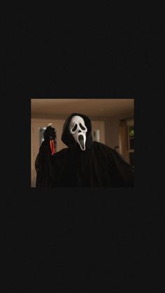 a person wearing a ghost mask and holding a black object in their right hand,