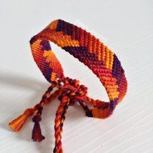 an orange, purple and yellow bracelet with tassels on it's end