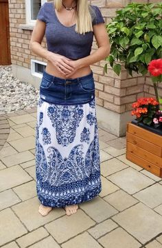 a woman standing in front of a brick building wearing a blue and white long skirt