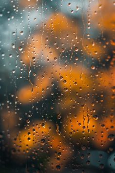 rain drops on the window with blurry buildings in the background and yellow traffic behind it