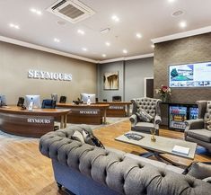 an office with couches, tables and televisions on the wall in front of them