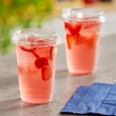 two plastic cups filled with drinks sitting on top of a table