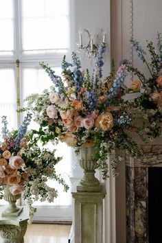 two vases filled with flowers next to a fireplace