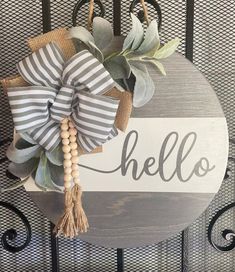 a wooden sign that says hello with a bow hanging from it's front door