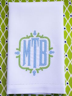 the monogrammed napkin is on top of a green and white tablecloth