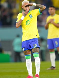 the soccer player is wiping his face while standing on the field