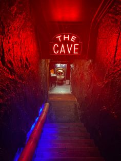 the cave sign is lit up in red, blue and purple light at the entrance