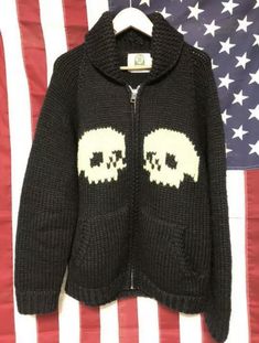 a black sweater with two skulls on it and an american flag in the back ground