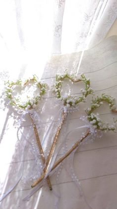 some flowers are sitting on a table near a window with white curtains and sheer drapes