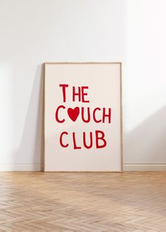 the couch club sign is displayed in front of a white wall with wood flooring