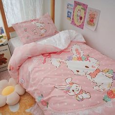 a pink bed with hello kitty sheets and pillowcases on the floor next to a window