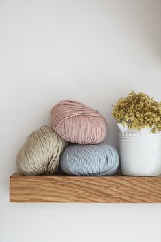 three skeins of yarn sitting on top of a wooden shelf