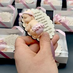 a hand holding a small piece of cake in front of many boxes with pink ribbons