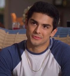 a man sitting in front of a couch wearing a blue and white t - shirt