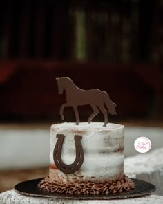 a white cake with a brown horse on top and a horseshoe cut out of it