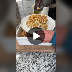 a person holding a plate with food in it on top of a counter next to an oven