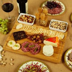 an assortment of cheeses, crackers, and meats on a wooden platter