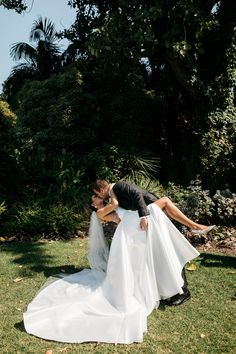 a bride and groom kissing in the grass