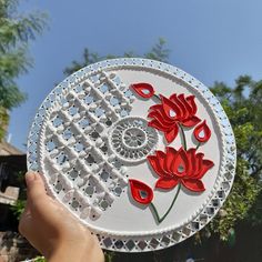 a hand holding a paper plate with red flowers on it