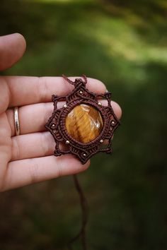 a hand holding a brooch with a tiger eye stone in it