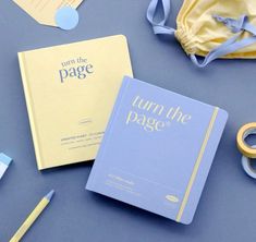 the contents of a baby's diaper laid out on a blue surface, including an open book and pacifier