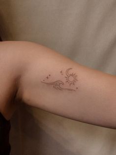 a woman's arm with a small sun and moon tattoo on the left arm