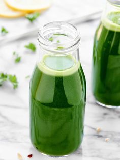 two jars filled with green liquid sitting on top of a table