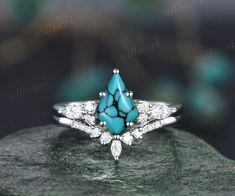 a turquoise and white diamond ring sitting on top of a rock