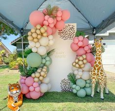 there is a large balloon arch with balloons and giraffes in the grass