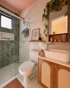 a white toilet sitting next to a walk in shower under a bathroom mirror above a sink