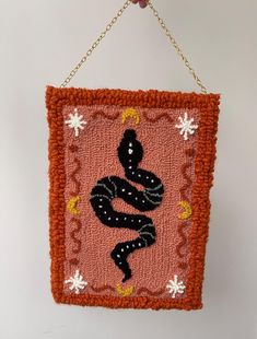 an orange and pink wall hanging with a black snake on it