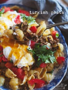 a blue and white plate topped with pasta, cheese and meat covered in sour cream