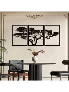 three black and white paintings on the wall above a dining room table with two chairs