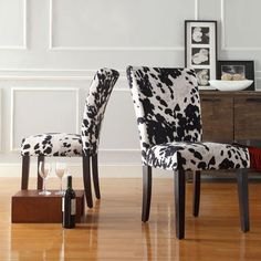 two chairs with black and white cow print upholstered backrests in a living room