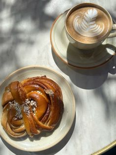 two plates with pastries on them next to a cup of cappuccino