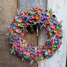 a colorful wreath is hanging on the side of a wooden door with an iron hook