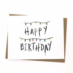 a card with the words happy birthday written on it and string lights hanging from them