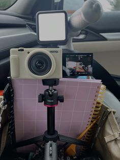 a camera sitting on top of a tripod next to a notebook and other items