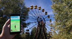 someone is holding up their cell phone to take a photo in front of a ferris wheel