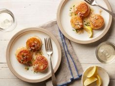 two white plates topped with scallops and lemon wedges