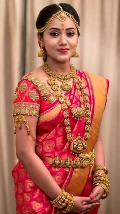 a woman in a red and gold sari with her hands on her hips, posing for